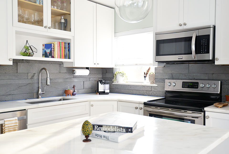 Norstone Planc tiles in platinum on a dodern kitchen with white countertops, white cabinets, and a small island